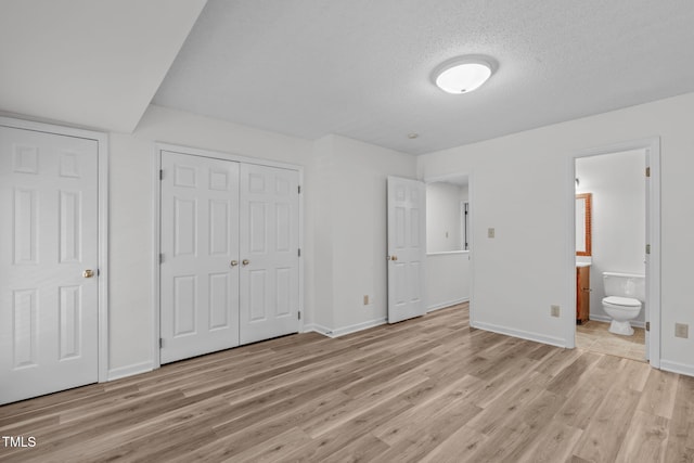 82 Forest Oaks Dr, Durham, NC 27705 - unfurnished bedroom featuring light wood-type flooring, a closet, ensuite bath, and a textured ceiling