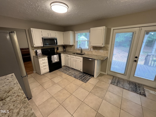 106 Carmel Woods Ct, Wake Forest, NC 27587 - kitchen featuring stainless steel appliances, white cabinets, decorative backsplash, a textured ceiling, and light tile patterned flooring
