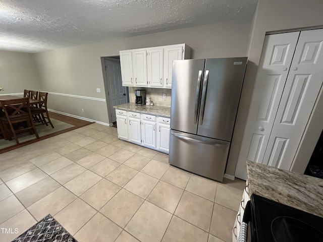 106 Carmel Woods Ct, Wake Forest, NC 27587 - kitchen with freestanding refrigerator, a textured ceiling, light tile patterned floors, white cabinets, and light stone counters