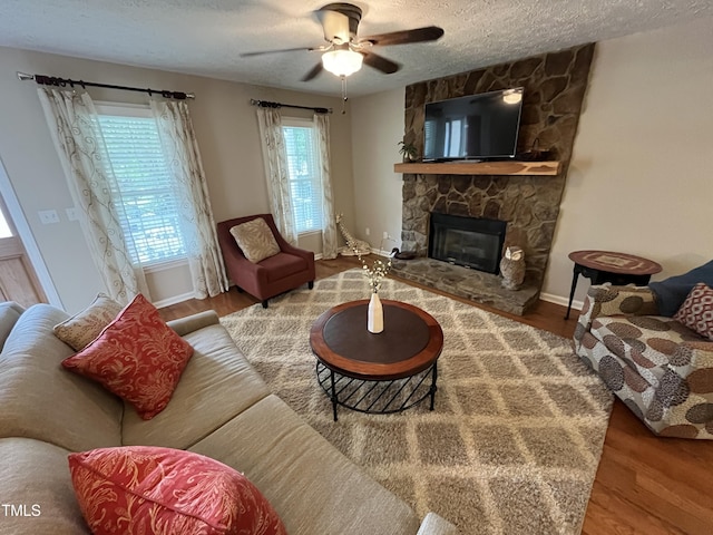 106 Carmel Woods Ct, Wake Forest, NC 27587 - living area featuring a textured ceiling, a ceiling fan, wood finished floors, and a stone fireplace