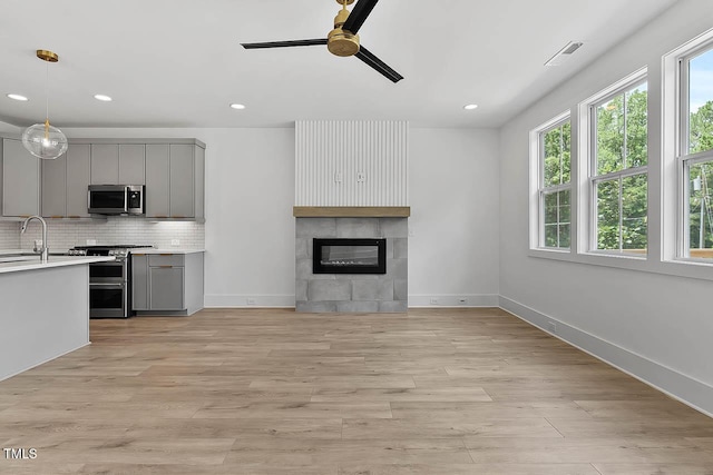 136 E End Ave, Durham, NC 27703 - unfurnished living room with ceiling fan, recessed lighting, light wood finished floors, and a tiled fireplace