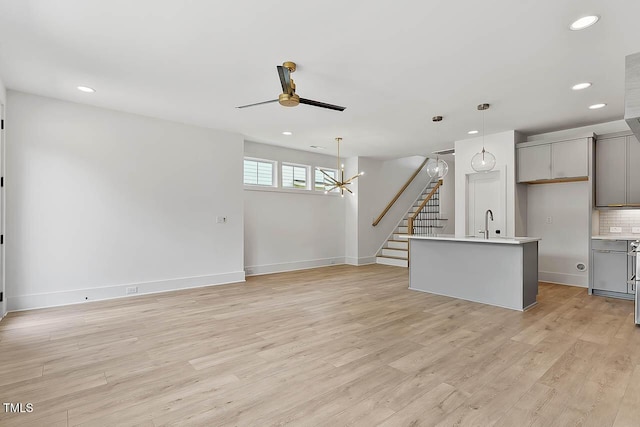 136 E End Ave, Durham, NC 27703 - unfurnished living room with ceiling fan, recessed lighting, light wood-type flooring, a chandelier, and stairway