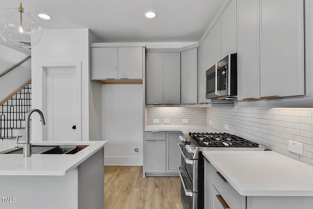 136 E End Ave, Durham, NC 27703 - kitchen with stainless steel appliances, gray cabinetry, light wood-style flooring, backsplash, and recessed lighting