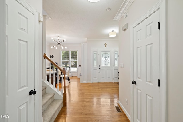 6425 Cross Ridge Dr, Holly Springs, NC 27540 - entryway with ornamental molding, stairs, a chandelier, light wood-type flooring, and a textured ceiling