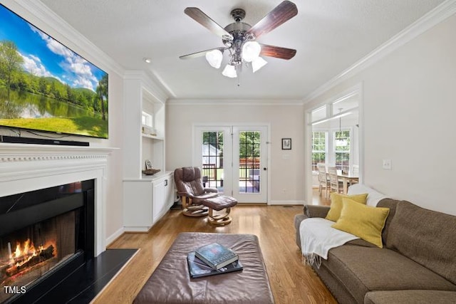 6425 Cross Ridge Dr, Holly Springs, NC 27540 - living room with ornamental molding, light wood-style floors, a lit fireplace, and ceiling fan