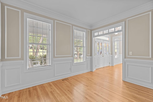 1806 White Dogwood Rd, Apex, NC 27502 - empty room featuring a decorative wall, ornamental molding, light wood-style flooring, and wainscoting