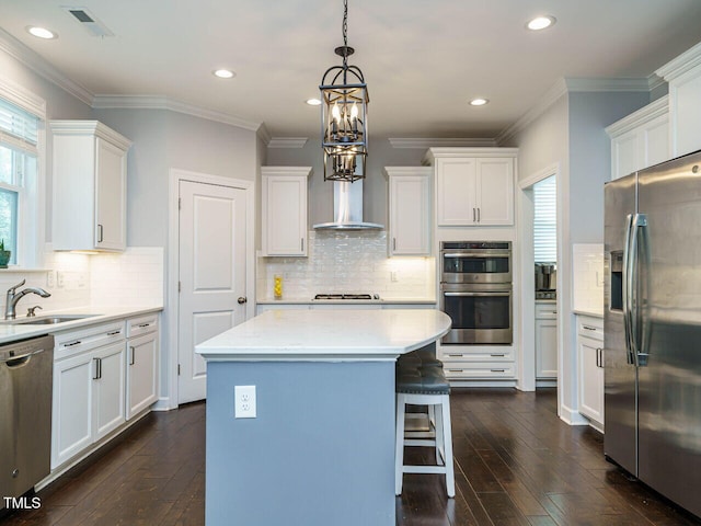 1004 Dogwood Bloom Ln, Knightdale, NC 27545 - kitchen with stainless steel appliances, a center island, white cabinets, ornamental molding, and recessed lighting