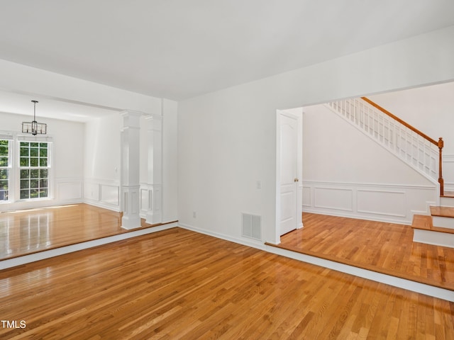 104 Pellinore Ct, Cary, NC 27513 - unfurnished living room featuring a decorative wall, wood finished floors, stairway, a chandelier, and wainscoting