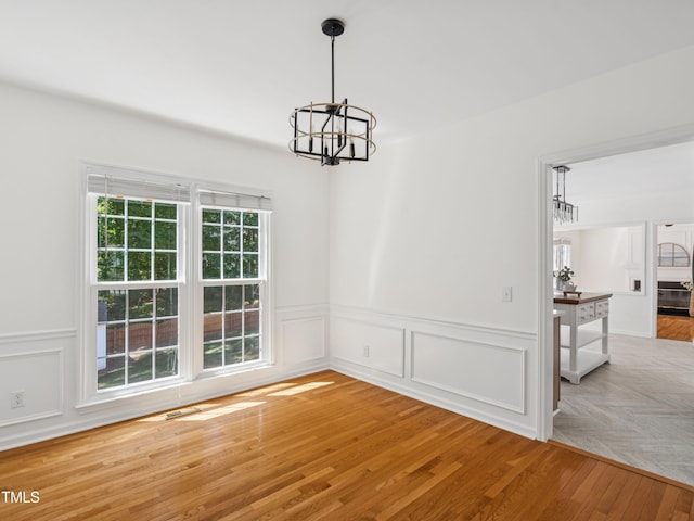 104 Pellinore Ct, Cary, NC 27513 - unfurnished dining area featuring a chandelier, wainscoting, wood finished floors, and a decorative wall