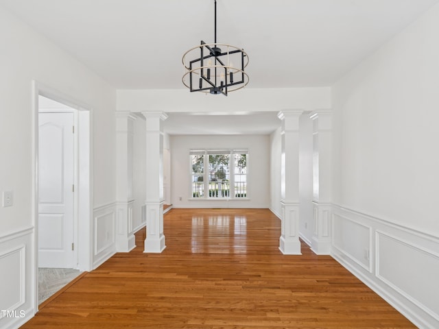 104 Pellinore Ct, Cary, NC 27513 - corridor featuring decorative columns, a chandelier, light wood-style flooring, a decorative wall, and wainscoting