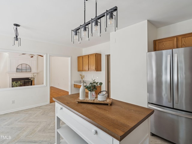 104 Pellinore Ct, Cary, NC 27513 - kitchen with freestanding refrigerator, brown cabinets, dark countertops, hanging light fixtures, and a center island