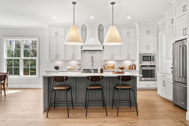 2105 Gardenbrook Dr, Raleigh, NC 27606 - kitchen with appliances with stainless steel finishes, premium range hood, light countertops, a center island with sink, and crown molding