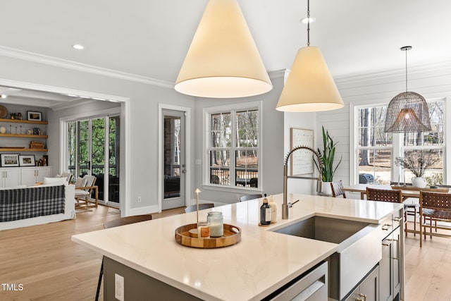 2105 Gardenbrook Dr, Raleigh, NC 27606 - kitchen featuring pendant lighting, ornamental molding, light wood-style flooring, an island with sink, and light stone counters