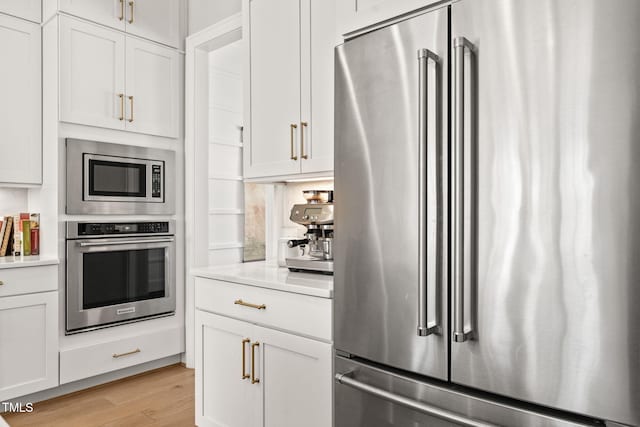 2105 Gardenbrook Dr, Raleigh, NC 27606 - kitchen with appliances with stainless steel finishes, light countertops, light wood-type flooring, and white cabinetry
