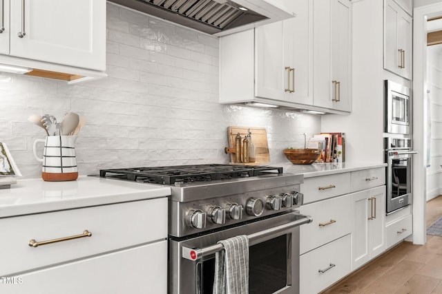 2105 Gardenbrook Dr, Raleigh, NC 27606 - kitchen with stainless steel appliances, premium range hood, tasteful backsplash, light countertops, and white cabinetry
