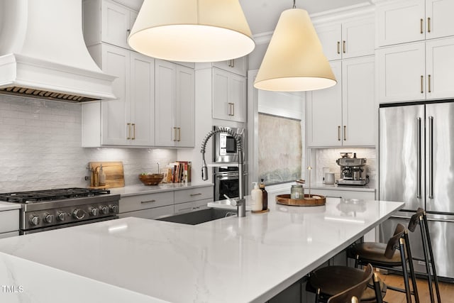 2105 Gardenbrook Dr, Raleigh, NC 27606 - kitchen with custom range hood, stainless steel appliances, decorative backsplash, a breakfast bar area, and decorative light fixtures