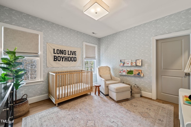 2105 Gardenbrook Dr, Raleigh, NC 27606 - bedroom with wallpapered walls, wood finished floors, and a nursery area