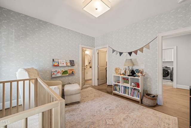 2105 Gardenbrook Dr, Raleigh, NC 27606 - bedroom featuring washer and clothes dryer, wallpapered walls, wood finished floors, and a nursery area