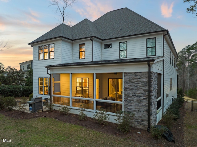 2105 Gardenbrook Dr, Raleigh, NC 27606 - back of property featuring a shingled roof, stone siding, and a sunroom