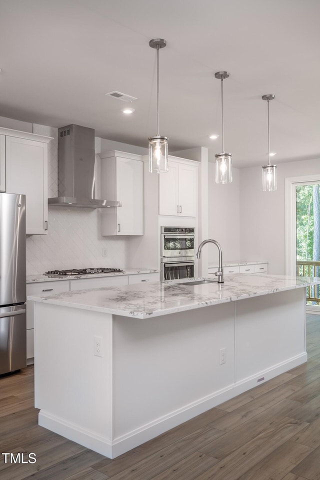 4703 Mint Leaf Ln, Raleigh, NC 27612 - kitchen featuring appliances with stainless steel finishes, wall chimney exhaust hood, a spacious island, backsplash, and dark wood-type flooring