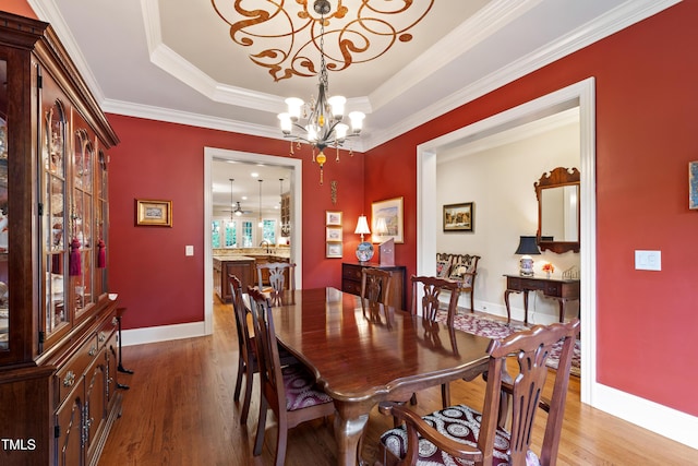 4164 English Garden Way, Raleigh, NC 27612 - dining room with a chandelier, wood finished floors, a tray ceiling, and ornamental molding