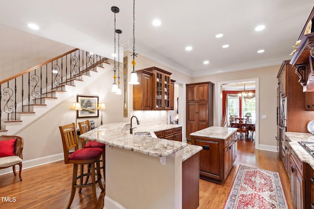 4164 English Garden Way, Raleigh, NC 27612 - kitchen with crown molding, brown cabinets, a chandelier, a kitchen bar, and a peninsula