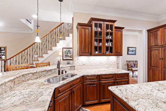 4164 English Garden Way, Raleigh, NC 27612 - kitchen with light stone counters, glass insert cabinets, hanging light fixtures, crown molding, and decorative backsplash