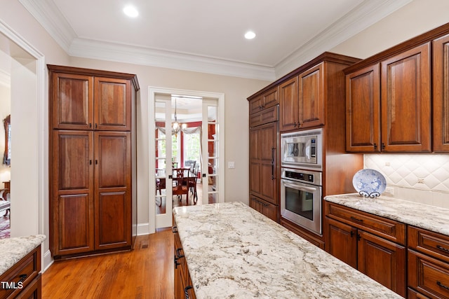 4164 English Garden Way, Raleigh, NC 27612 - kitchen with appliances with stainless steel finishes, decorative backsplash, light stone countertops, light wood finished floors, and crown molding