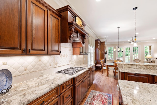 4164 English Garden Way, Raleigh, NC 27612 - kitchen featuring stainless steel gas cooktop, light wood-type flooring, healthy amount of natural light, light stone counters, and crown molding