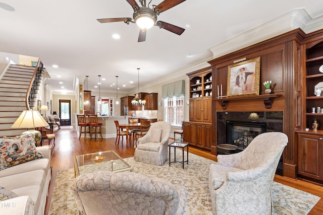 4164 English Garden Way, Raleigh, NC 27612 - living room featuring light wood-style flooring, a high end fireplace, a ceiling fan, ornamental molding, and stairs