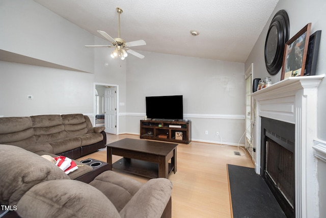 104 Fairfield Dr, Goldsboro, NC 27530 - living room featuring a fireplace with flush hearth, light wood-style flooring, ceiling fan, a textured ceiling, and high vaulted ceiling
