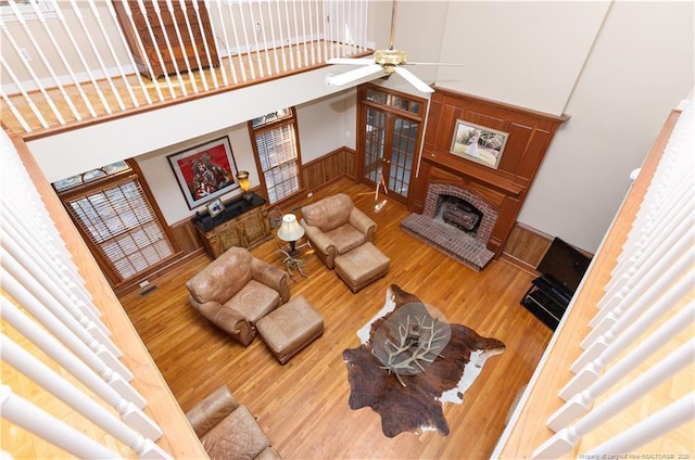 387 Three Bridge Rd, Dunn, NC 28334 - living area with a brick fireplace, wood finished floors, wainscoting, ceiling fan, and a towering ceiling