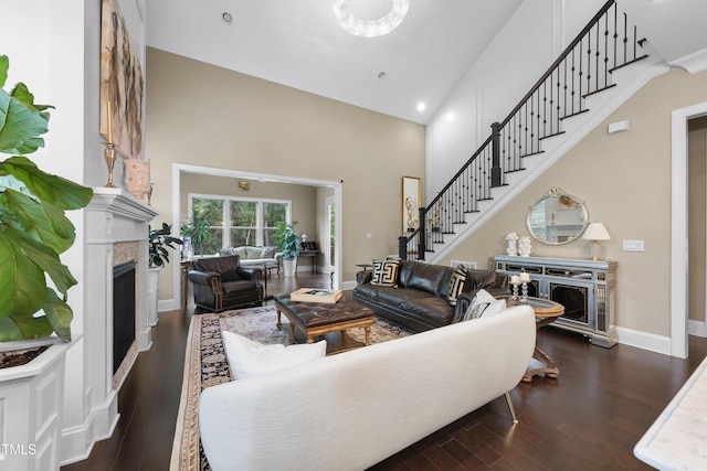1089 Queensdale Dr, Cary, NC 27519 - living room featuring a high end fireplace, dark wood finished floors, a towering ceiling, stairway, and recessed lighting