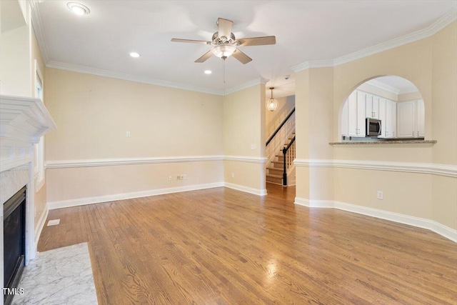 109 Gullane Ct, Apex, NC 27502 - unfurnished living room with ceiling fan, a high end fireplace, stairs, light wood-type flooring, and recessed lighting