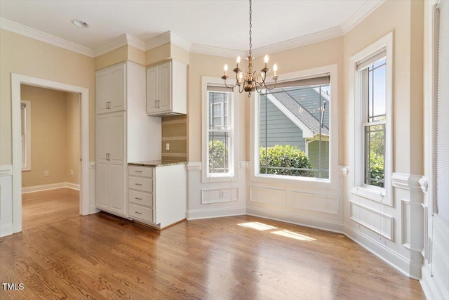 109 Gullane Ct, Apex, NC 27502 - unfurnished dining area with a chandelier, light wood-type flooring, a wainscoted wall, a decorative wall, and ornamental molding