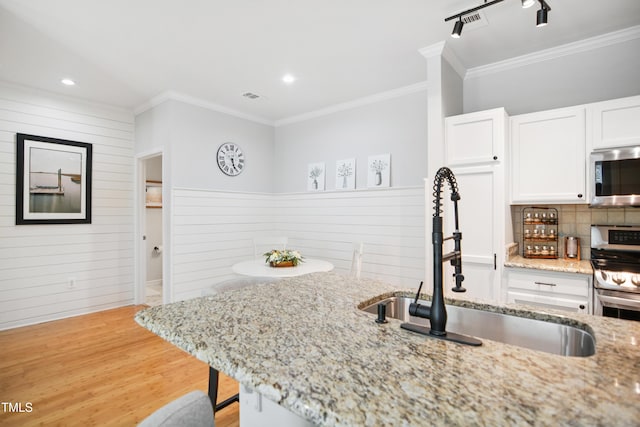 105 Fountain Ridge Pl, Holly Springs, NC 27540 - kitchen with appliances with stainless steel finishes, white cabinets, crown molding, light wood finished floors, and light stone counters
