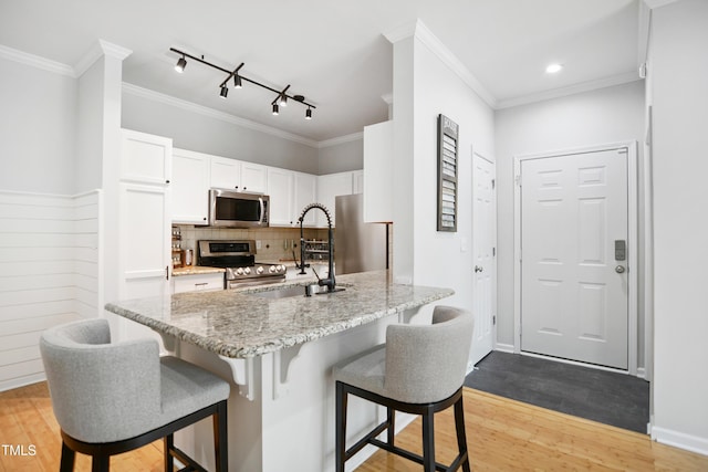 105 Fountain Ridge Pl, Holly Springs, NC 27540 - kitchen with appliances with stainless steel finishes, a breakfast bar, white cabinetry, light wood finished floors, and light stone counters