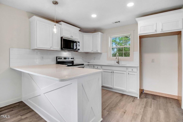 400 E Townsend St, Dunn, NC 28334 - kitchen with stainless steel appliances, a peninsula, white cabinets, backsplash, and recessed lighting