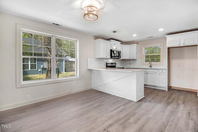400 E Townsend St, Dunn, NC 28334 - kitchen with stainless steel appliances, backsplash, light wood-type flooring, white cabinetry, and recessed lighting