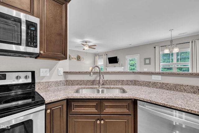 115 Creech Place Dr, Benson, NC 27504 - kitchen with stainless steel appliances, dark brown cabinets, ceiling fan, and light stone counters