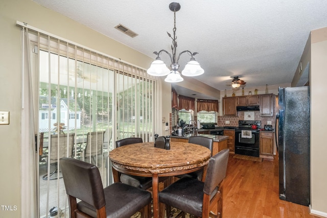 501 Dandelion Ct, Raleigh, NC 27610 - dining room featuring a chandelier, light wood-type flooring, a ceiling fan, and a textured ceiling