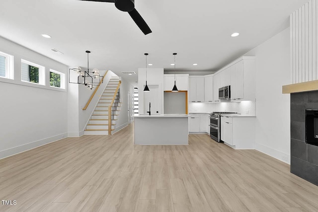 140 E End Ave, Durham, NC 27703 - kitchen featuring appliances with stainless steel finishes, a ceiling fan, decorative light fixtures, tasteful backsplash, and light wood-style floors