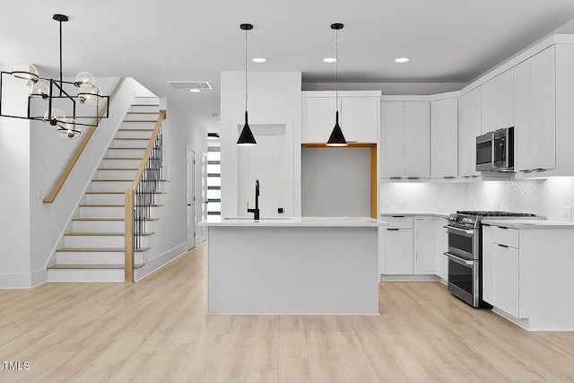 140 E End Ave, Durham, NC 27703 - kitchen featuring appliances with stainless steel finishes, a chandelier, light wood finished floors, tasteful backsplash, and light countertops