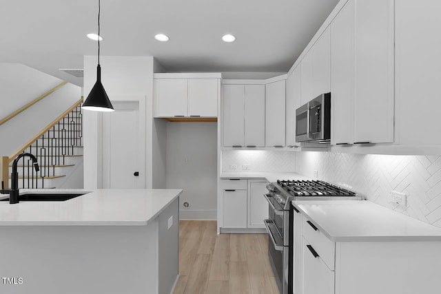140 E End Ave, Durham, NC 27703 - kitchen featuring stainless steel appliances, light wood-style floors, white cabinetry, decorative backsplash, and pendant lighting