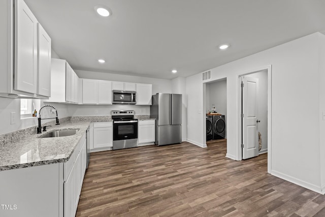 9059 Shallow Creek Trl, Bailey, NC 27807 - kitchen featuring stainless steel appliances, washing machine and dryer, dark wood-type flooring, recessed lighting, and white cabinetry
