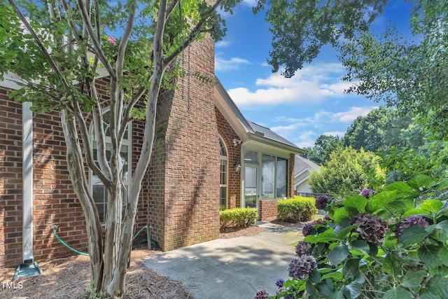 4710 Ludwell Branch Ct, Raleigh, NC 27612 - view of home's exterior featuring brick siding, a chimney, a patio, and roof with shingles