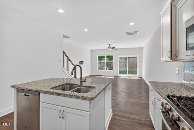 305 Lionel St, Durham, NC 27705 - kitchen featuring appliances with stainless steel finishes, ceiling fan, open floor plan, an island with sink, and dark wood-style flooring