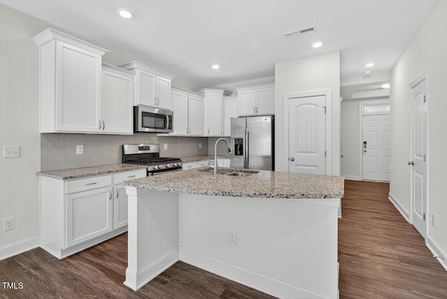 305 Lionel St, Durham, NC 27705 - kitchen with appliances with stainless steel finishes, white cabinetry, dark wood-style flooring, a center island with sink, and tasteful backsplash