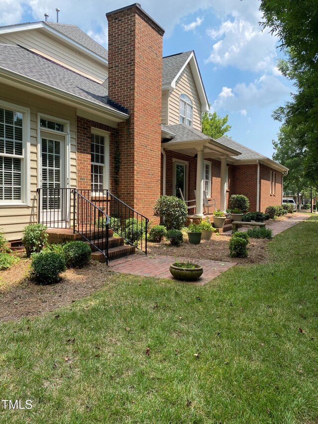 3802 Burwell Rollins Cir, Raleigh, NC 27612 - view of front facade with a chimney, a front lawn, brick siding, a patio, and a shingled roof