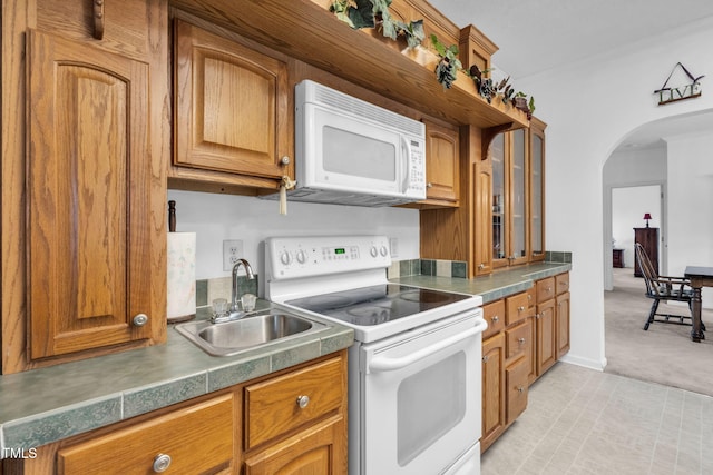 9633 Grassy Creek Rd, Bullock, NC 27507 - kitchen featuring white appliances, brown cabinetry, arched walkways, light colored carpet, and glass insert cabinets